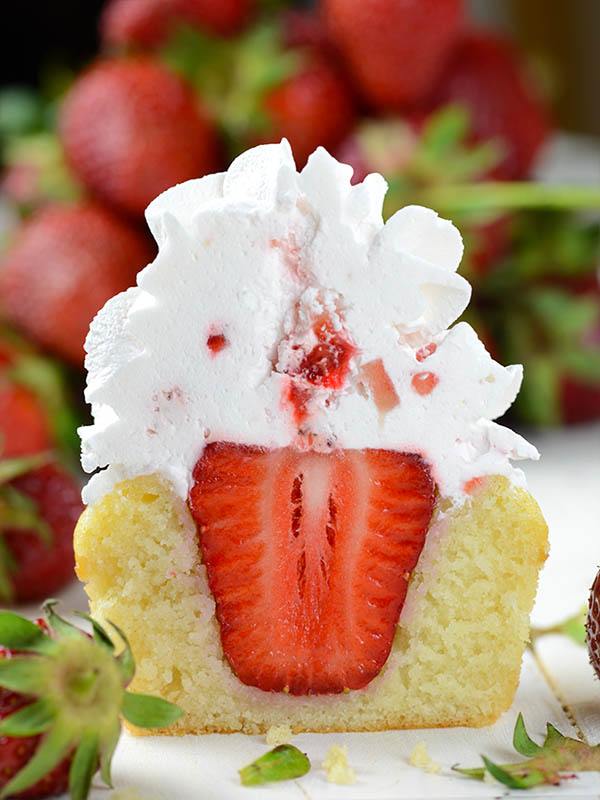 Half sliced Strawberry Shortcake Cupcake with a big strawberry .