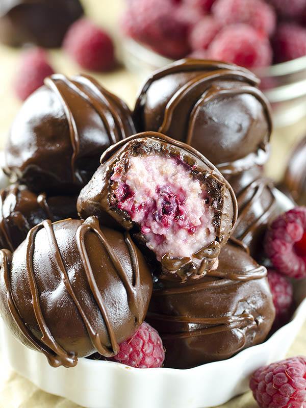 One bitten Raspberry Cheesecake Truffle in a bunch of truffles.