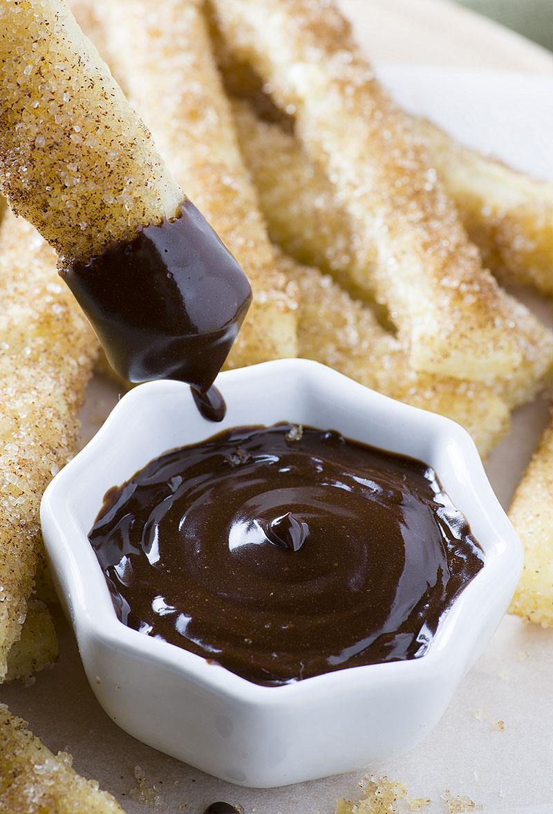 15 Minutes Churro Sticks â€“ easy, crispy sticks made with puff pastry, rolled in melted butter and coated with cinnamon-sugar mixture, served with warm chocolate dipping sauce 