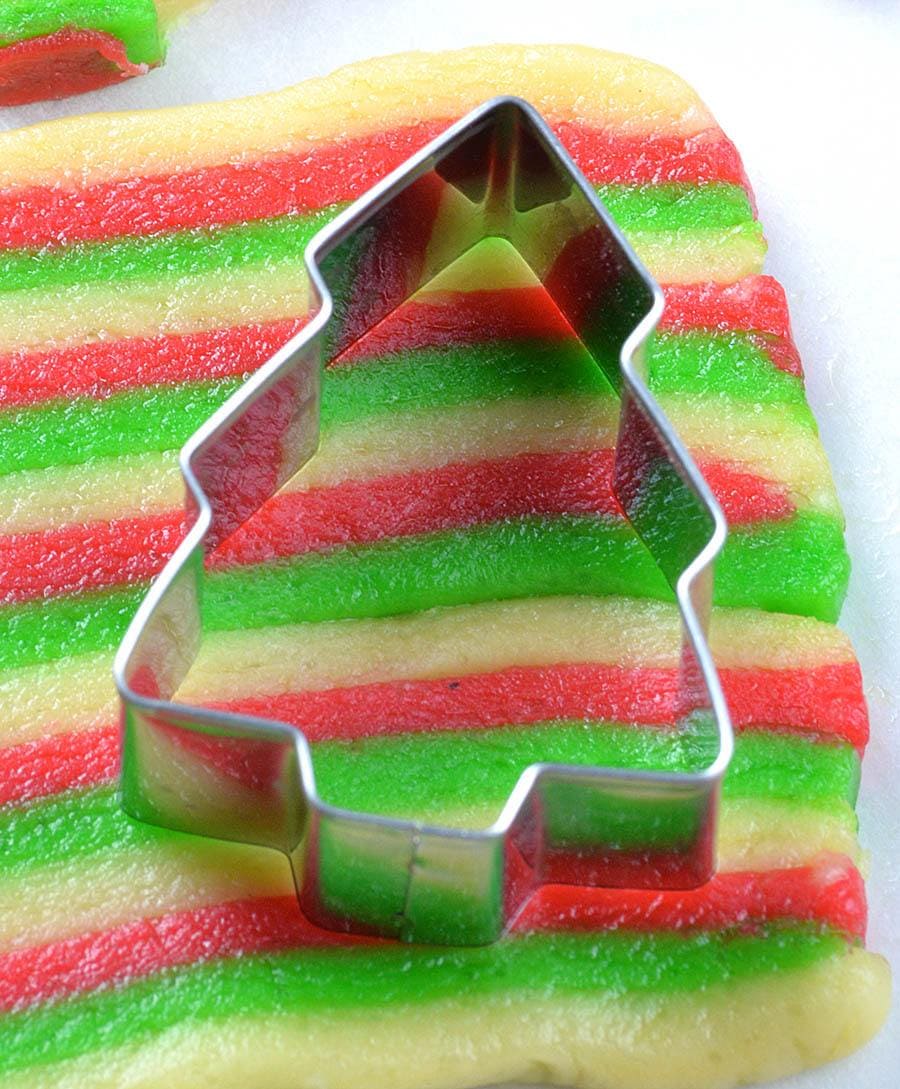 Christmas tree cookie cutter on three colors cookie dough.