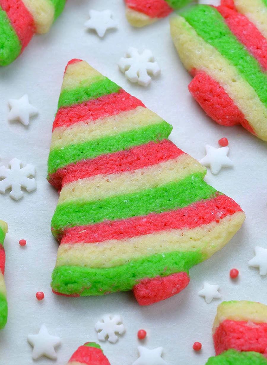 Red,green and white colors layered Christmas sugar cookies on the table with sprinkles and show flake decoration.