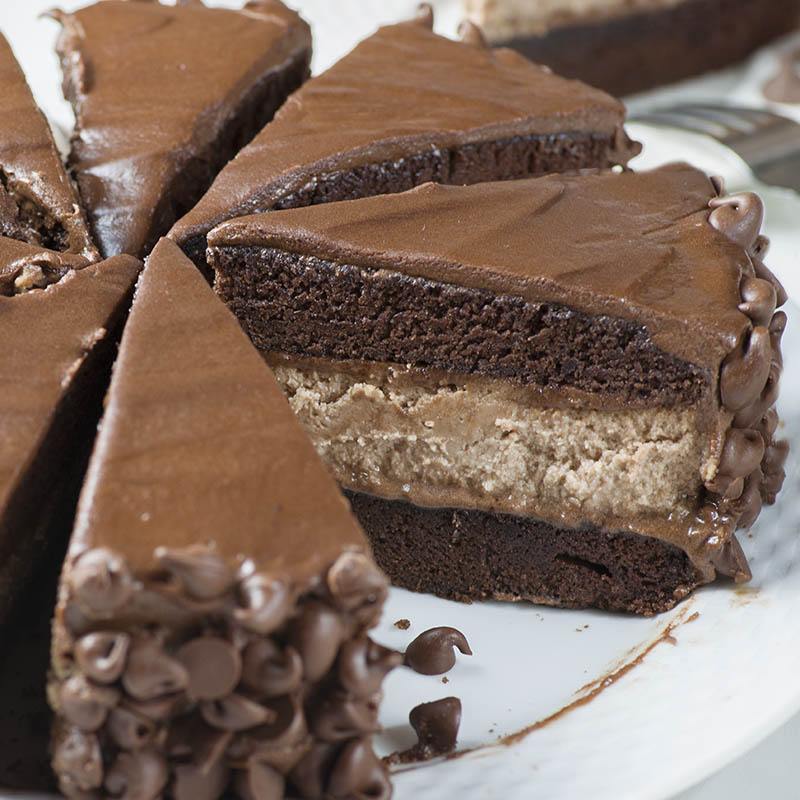 Zoomed piece of Hershey Cheesecake Chocolate Cake in plate with whole sliced cake.
