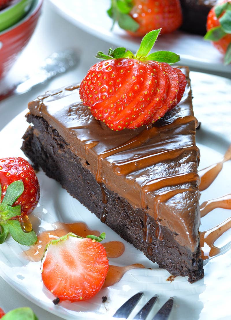 Piece of Flourless Chocolate Cake on a white plate garnished with strawberry.