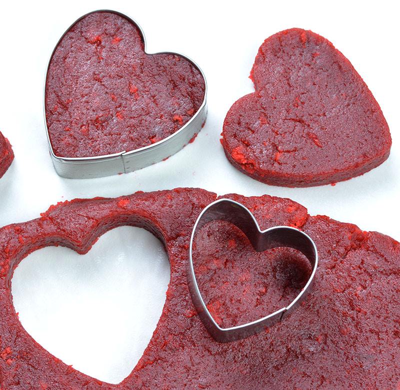 Red velvet cake dough with heart shaped cookie cutter.