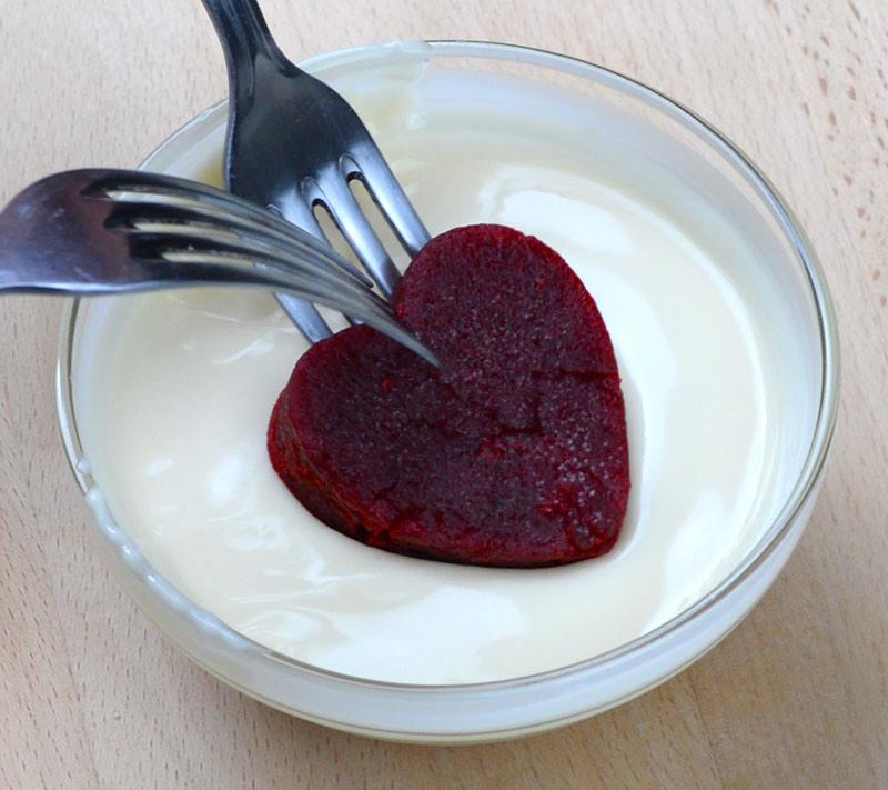 Heart shaped red velvet cake dough dipped into white chocolate.
