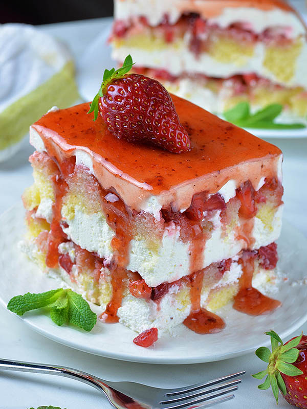 Strawberry Icebox Shortcake auf weißem Teller mit Erdbeere an der Spitze.