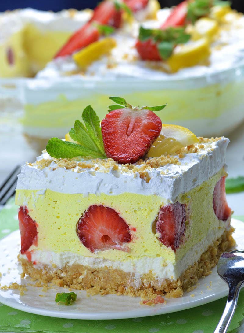 Piece of Strawberry Lemonade Lasagna on white plate and full plate of this strawberry dessert behind the piece.