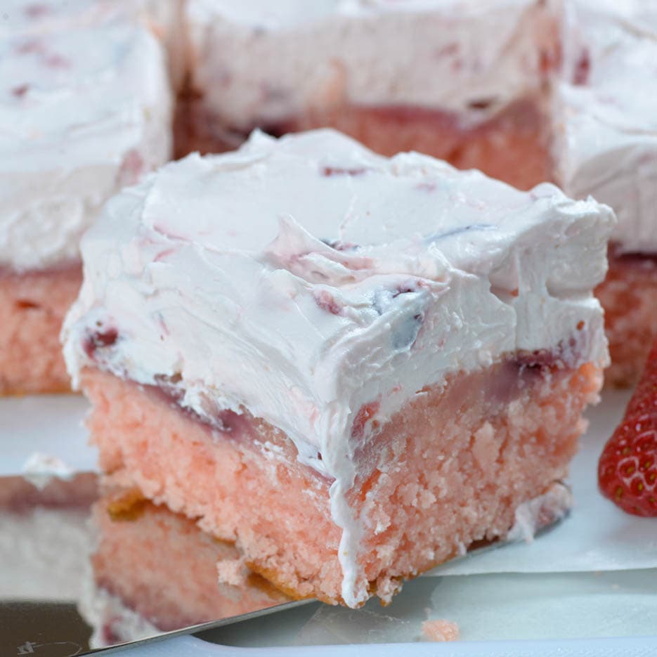 Big slice of Strawberry sheet cake in front of many other pieces.