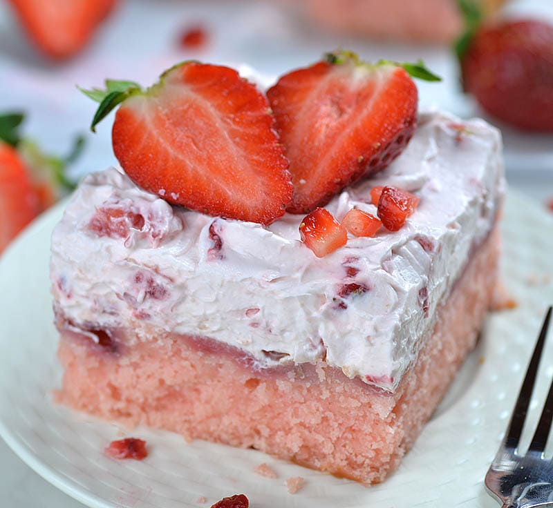 Strawberry sheet cake piece on a plate garnished with split strawberry.