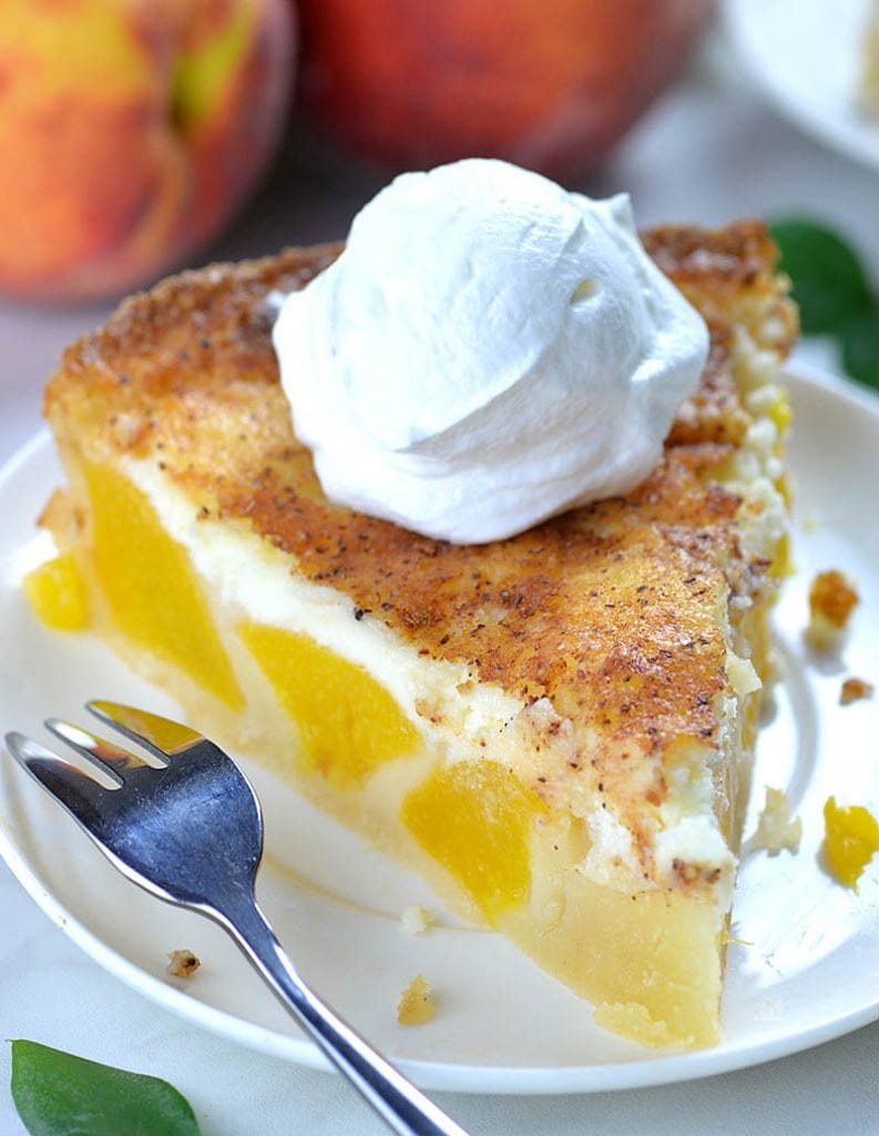 Piece of Peach and Cream Pie on a white plate garnished with whipped cream on top.