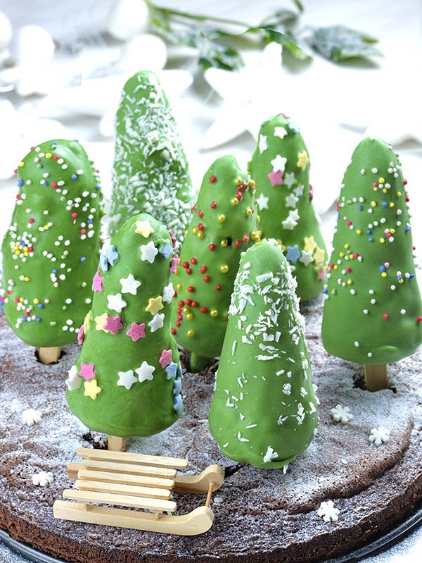 Christmas Tree Cheesecake on a stick on a chocolate cake in form of snow forest.