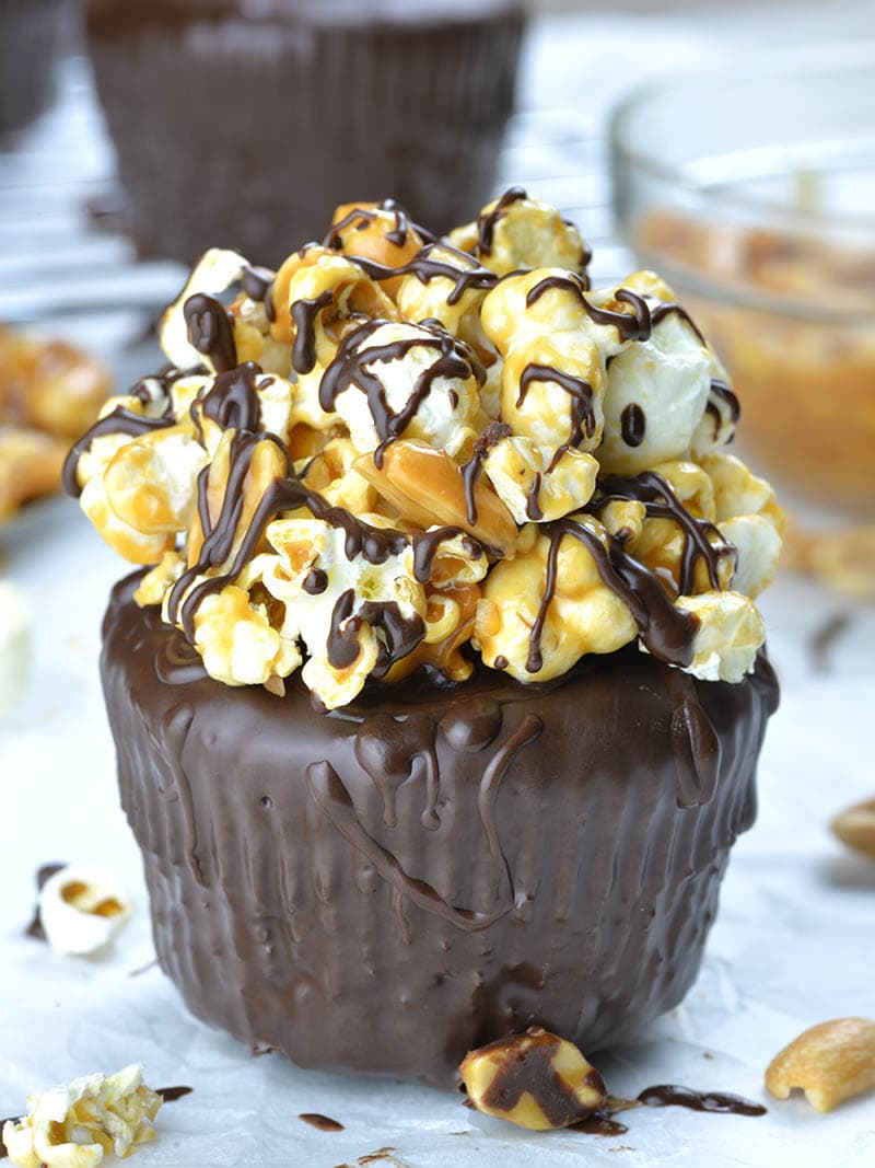 Chocolate cupcakes garnished with salted caramel, peanuts and popcorn .