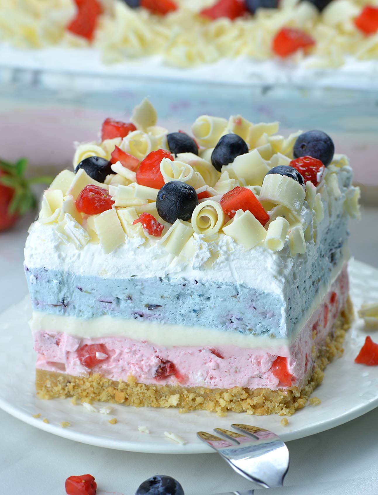 Big slice of Very Berry Dessert Lasagna - White layer in the middle is no bake cheesecake. Then, there’s blue layer-fresh blueberry mousse with Greek yogurt, berry blue Jello and whipped cream, too.