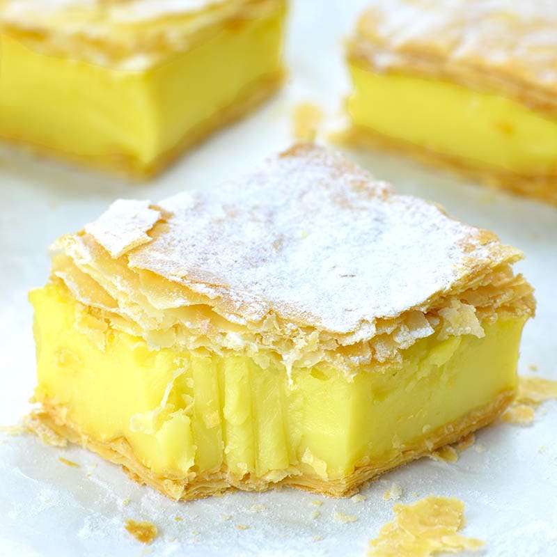 Vegan lemon custard slice with puff pastry crust dusted with powdered sugar.