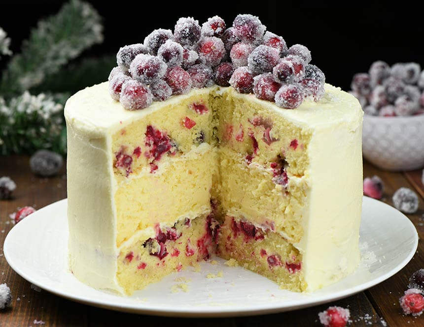 Whole White Chocolate Cranberry Cheesecake Cake with few pieces missing in the center.