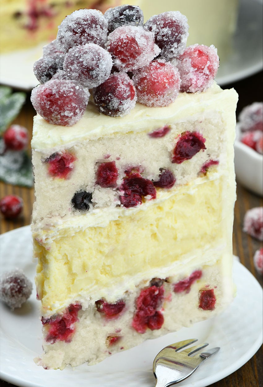 White Chocolate Cranberry Cheesecake Cake - Layers of moist vanilla cake made with fresh cranberries, creamy white chocolate cheesecake, and silky white chocolate frosting, garnished with sparkling cranberries.