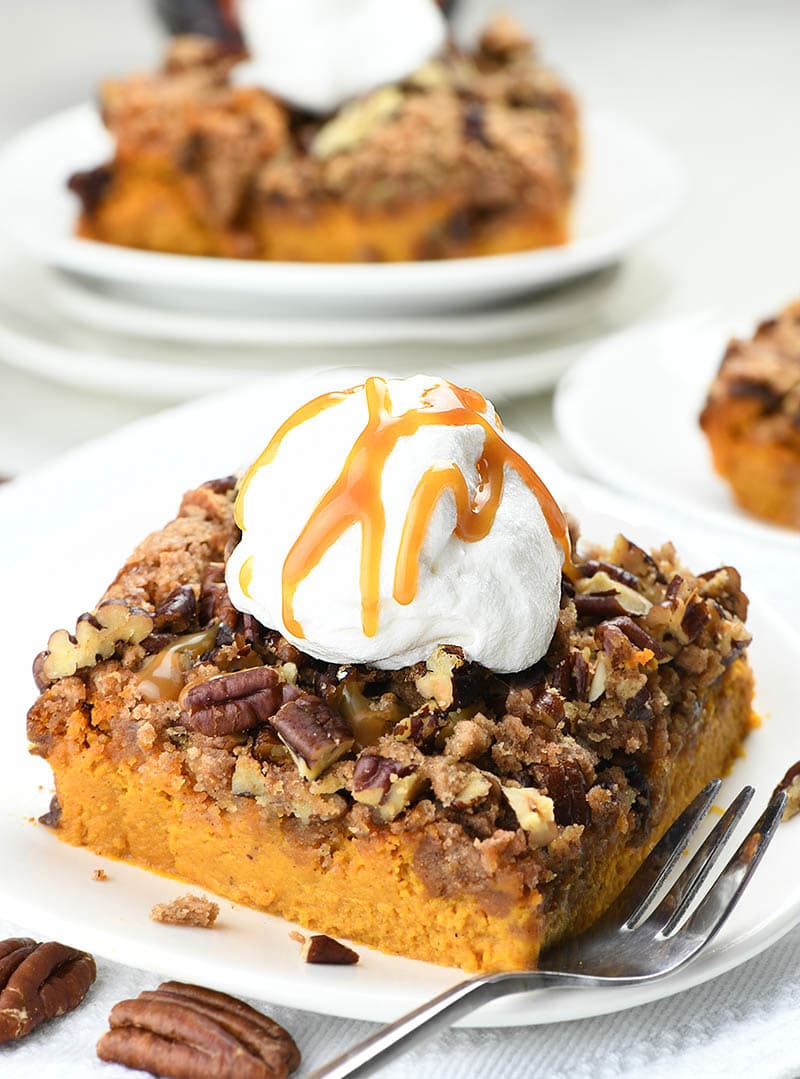 Pecan Pumpkin Crunch Cake on a white plate with scoop of whipped cream on top.