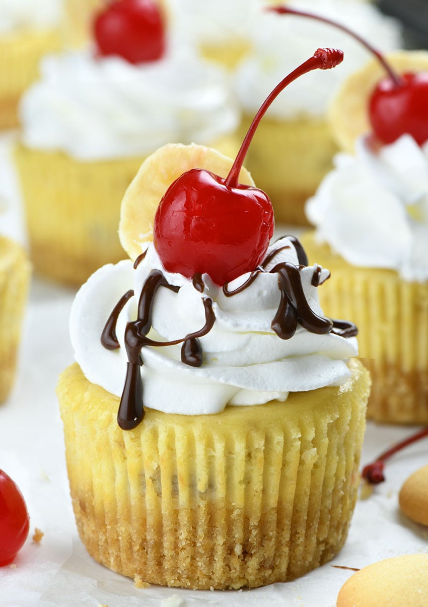 Mini Banana Split Cheesecakes packed with banana flavor, perfect for spring baking season. Smooth and creamy banana cheesecake, vanilla wafer crust and whipped cream topping garnished with banana slices and maraschino cherries