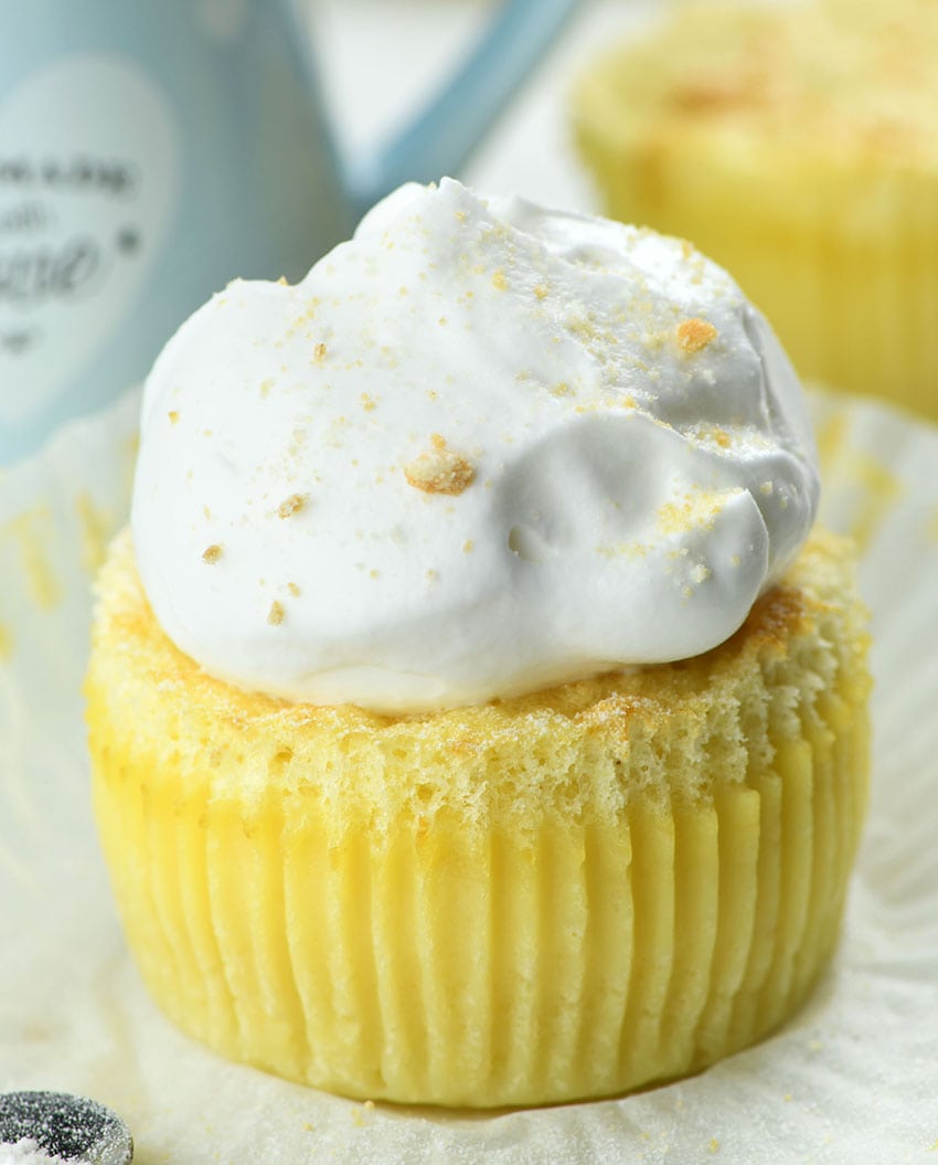 Vanilla Magic Custard Cupcake on parchment paper topped with whipped cream.