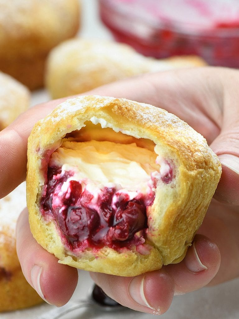 Cherry Cheesecake Crescent Muffin cut in half with couple of muffins behind it.