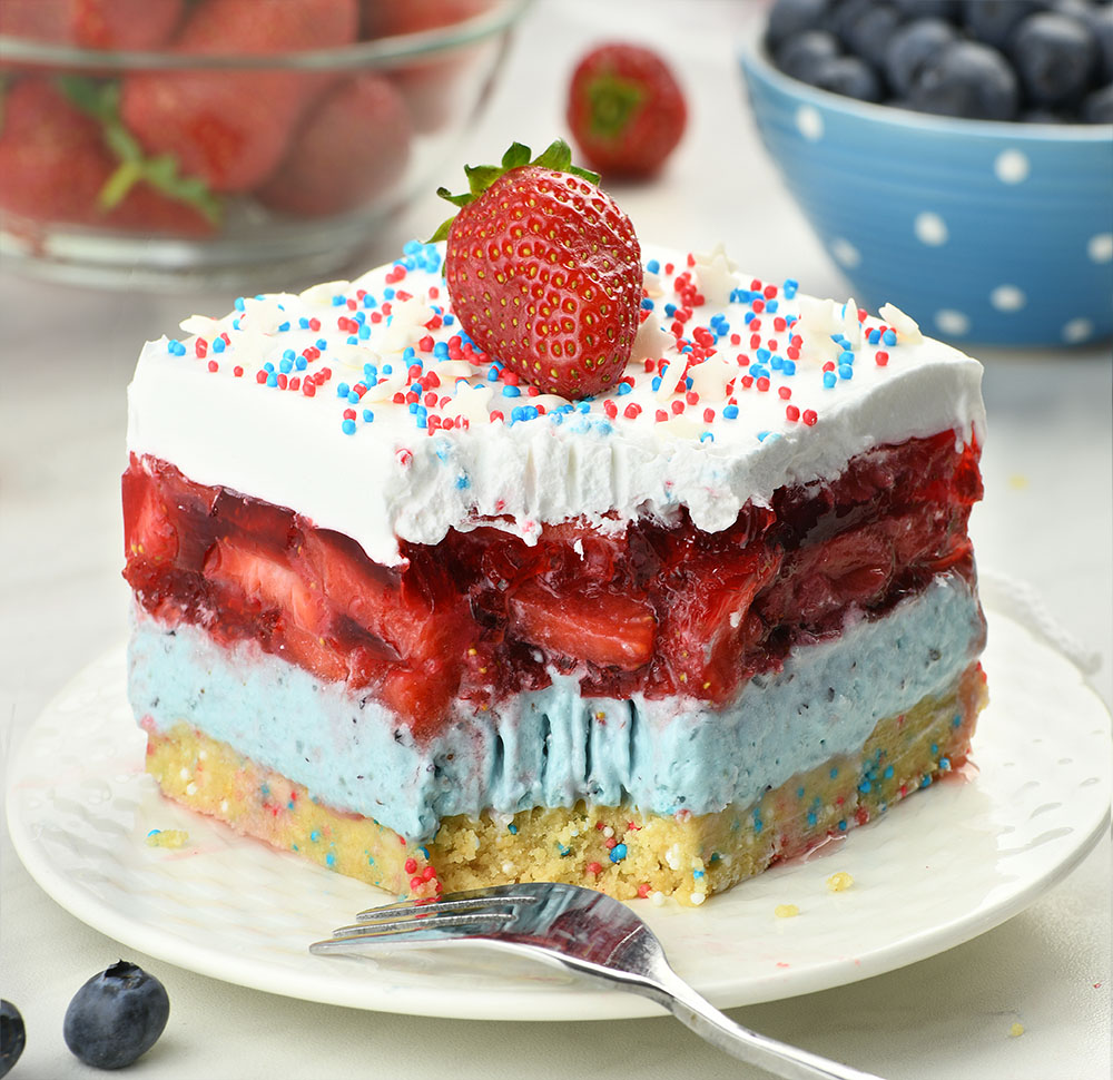 Summer Berry Jello Lasagna - red, white and blue colors layered dessert on a white plate.