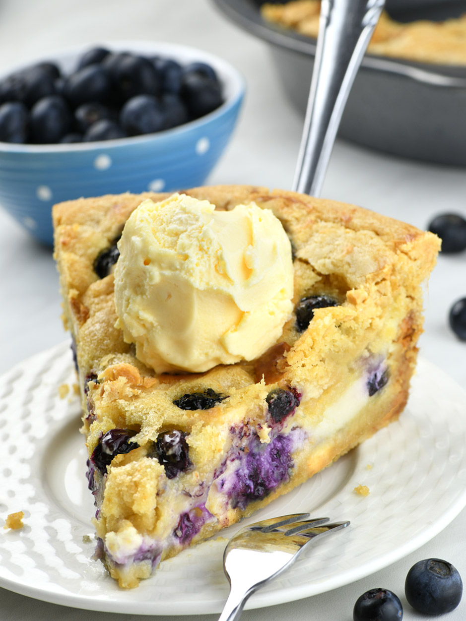 Blueberry Cheesecake Cookie Pie on a white plate with a blueberry jar behind.
