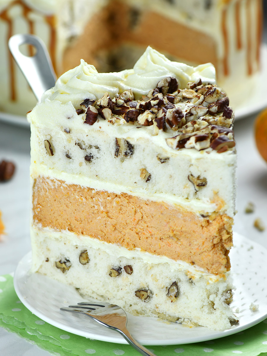 Delicate white cake layers dotted with pecans, and silky cream cheese buttercream frosting on a white plate.