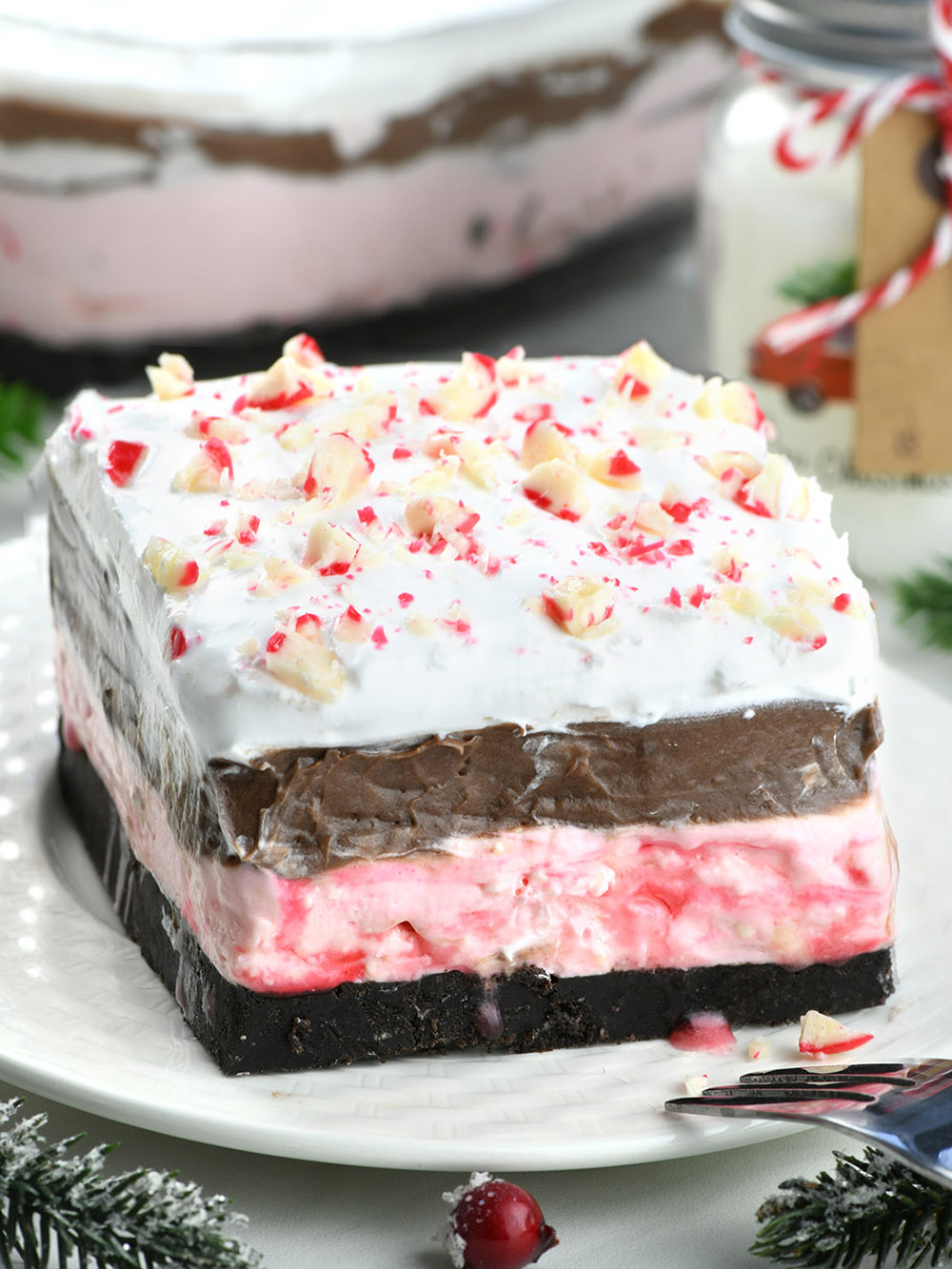 Piece of layered Chocolate Peppermint Lasagna  on a white plate with a Christmas decorations.