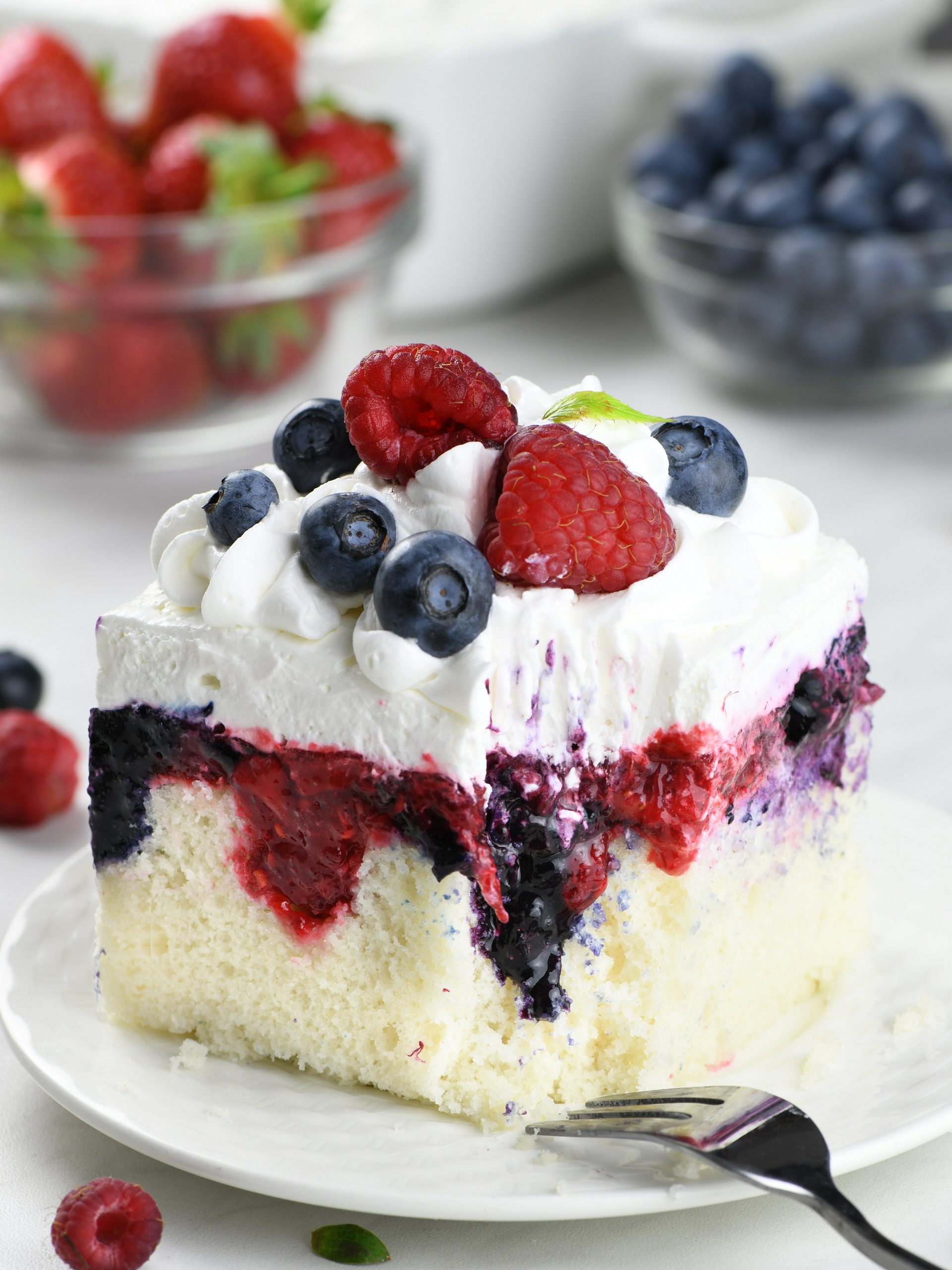 Bursting with the fresh and vibrant flavors of summer, this Summer Berry Poke Cake effortlessly combines the sweet tartness of blueberries, strawberries, and raspberries, crowned with a light, airy whipped cream.