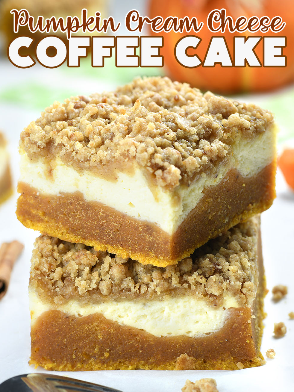 Two pieces of Pumpkin Surf Cheese Coffee Confection with streusel crumbs on the top, with pumpkin decoration behind.