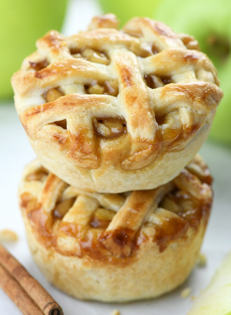 Two small slices of apple pie on top of each other with Green Smith apples as a decoration behind them.