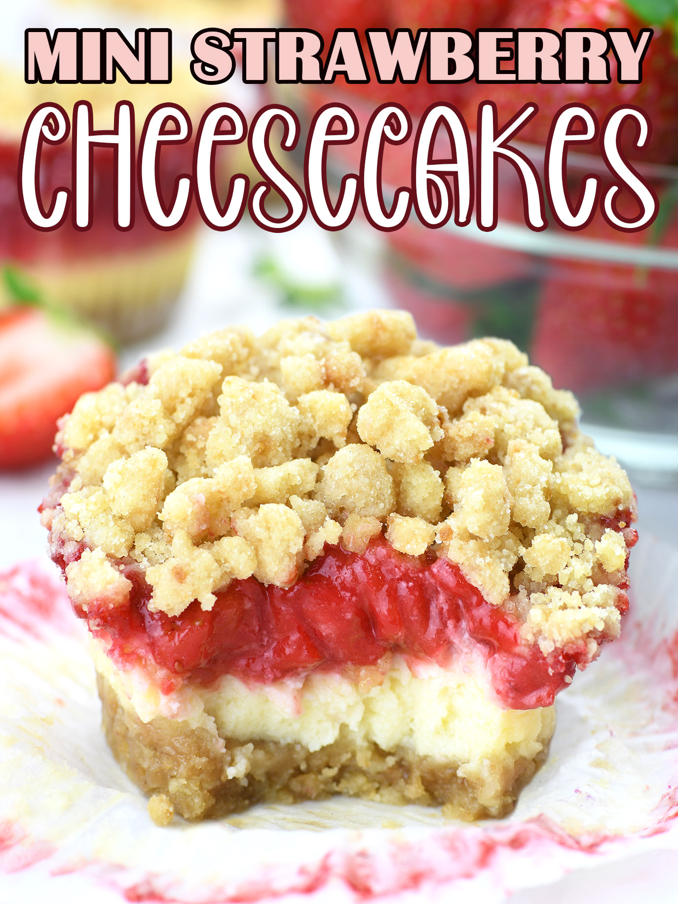 mini strawberry cheesecake with a crumble topping. It looks homemade and delicious, showcasing a cross-section of the dessert with distinct layers. The base appears to be a golden-brown crumb crust, topped with a layer of creamy cheesecake filling, followed by a vibrant red strawberry layer, and finished with a generous amount of golden crumble topping. The colors are quite rich, suggesting a ripe strawberry topping and a well-baked crust. It’s presented unwrapped from its baking liner, suggesting it’s ready to be enjoyed.
