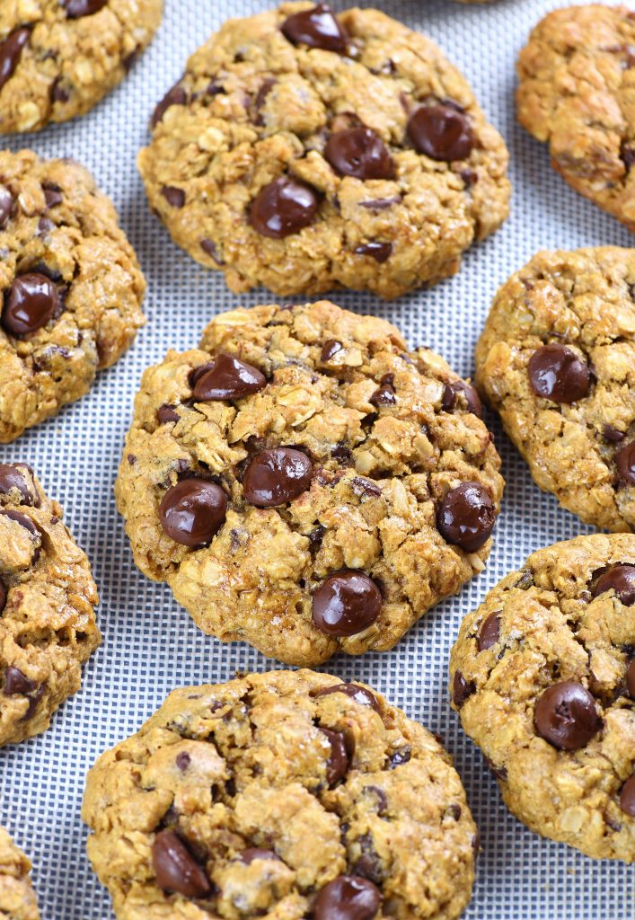 A batch of freshly baked oatmeal chocolate chip cookies placed on a baking mat, showcasing their golden texture, hearty oats, and gooey chocolate chips.