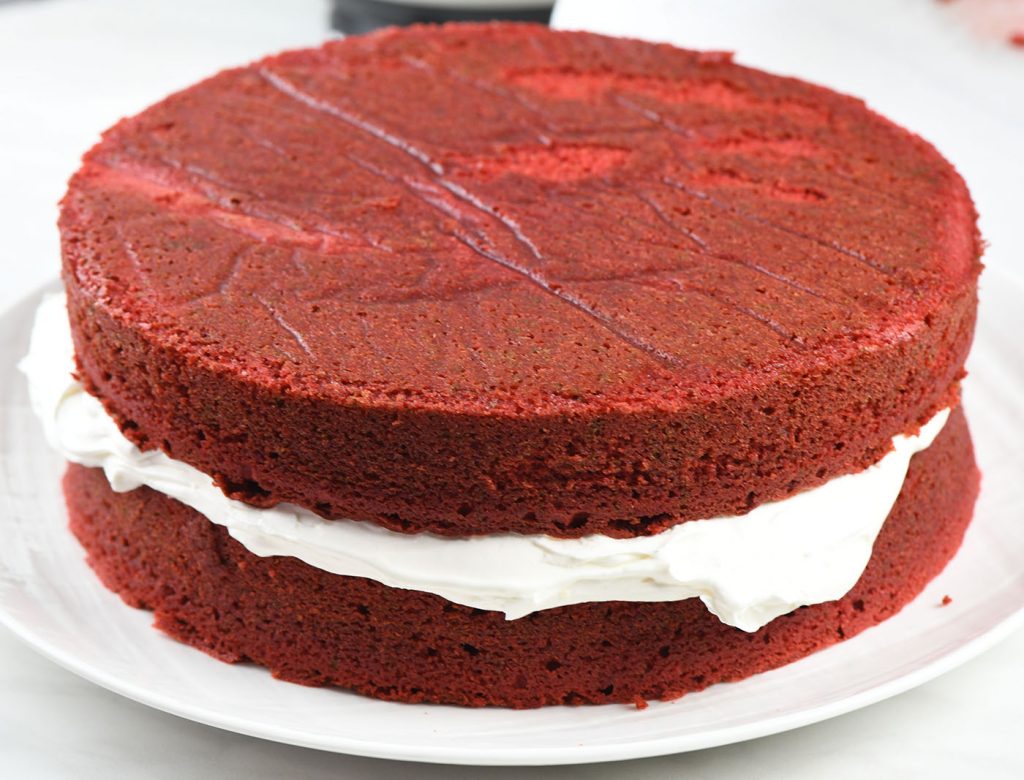 Two layers of red velvet cake stacked with a thick layer of cream cheese frosting in between, forming the base of the Red Velvet Cake.