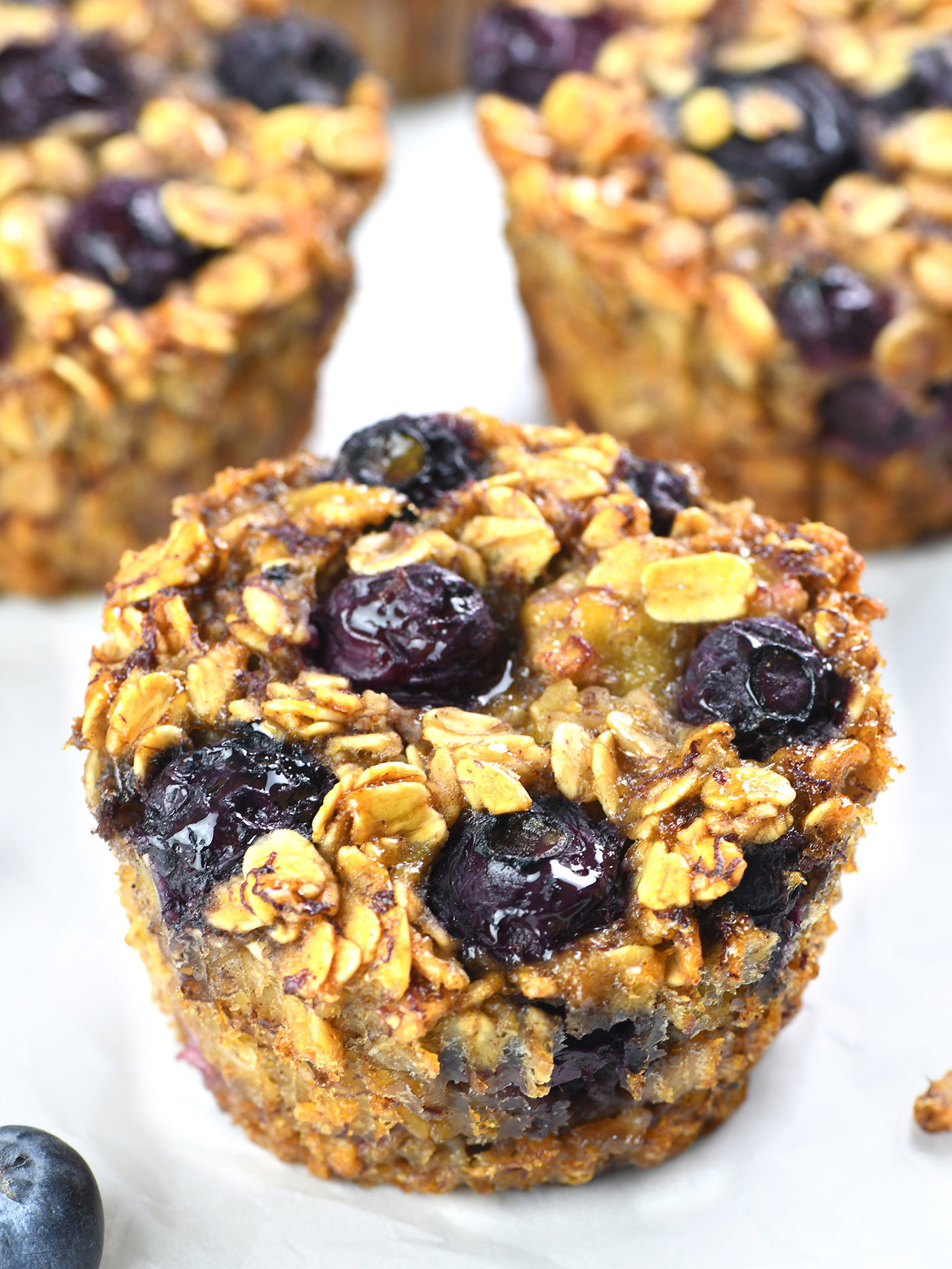 Close-up of a Blueberry Banana Baked Oatmeal Cup topped with fresh blueberries and a golden oat crust.