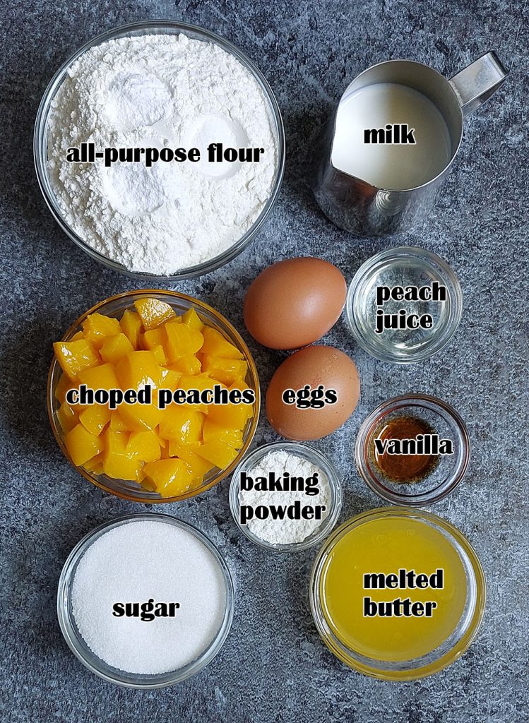 Flat lay of peach muffin ingredients including all-purpose flour, milk, chopped peaches, sugar, eggs, peach juice, baking powder, vanilla, and melted butter on a dark stone background.